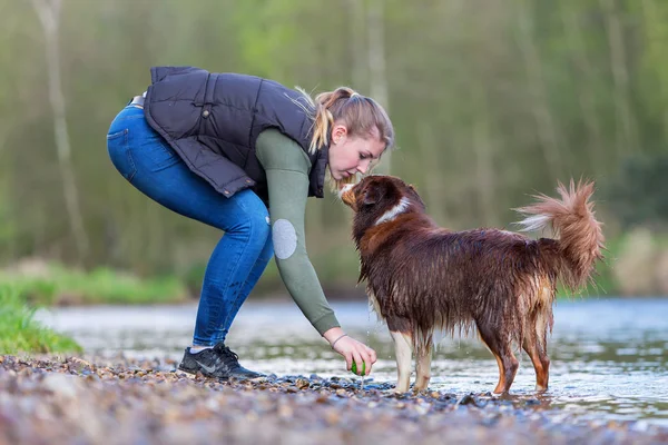 Jovem mulher com seu cão no rio — Fotografia de Stock