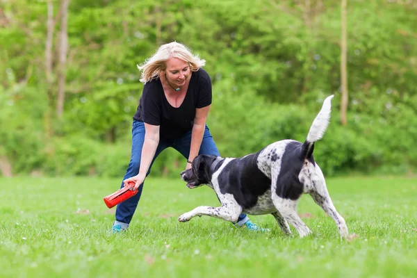 Mulher brinca com seu cão ao ar livre — Fotografia de Stock