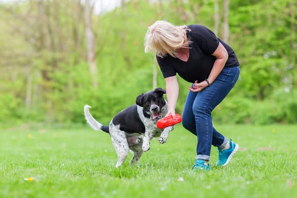 Mulher brinca com seu cão ao ar livre — Fotografia de Stock