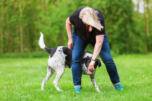 Mulher brinca com seu cão ao ar livre — Fotografia de Stock