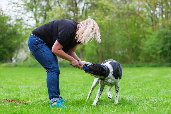 Mulher brinca com seu cão ao ar livre — Fotografia de Stock