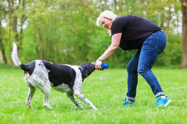 Mulher brinca com seu cão ao ar livre — Fotografia de Stock