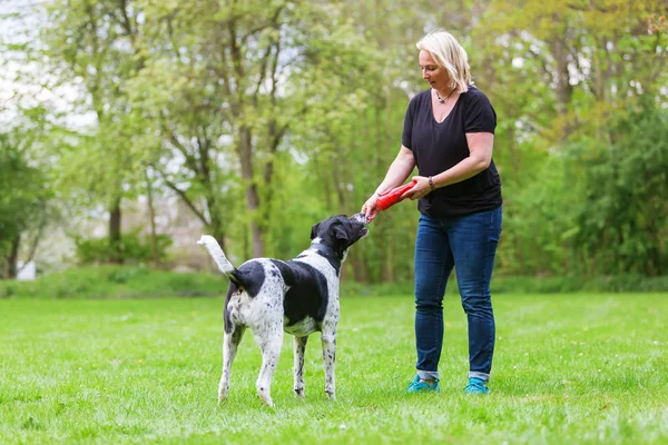 Mulher brinca com seu cão ao ar livre — Fotografia de Stock