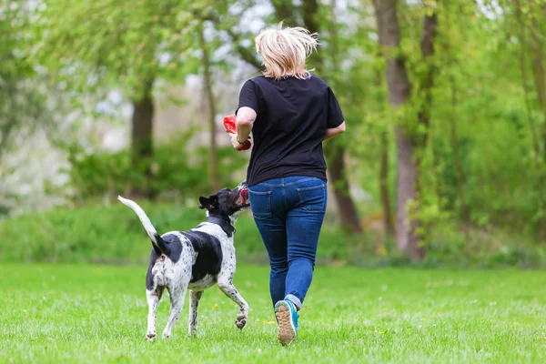 Mulher brinca com seu cão ao ar livre — Fotografia de Stock