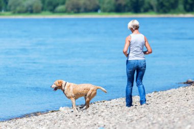 nehir kenarında bir köpekle Olgun kadın