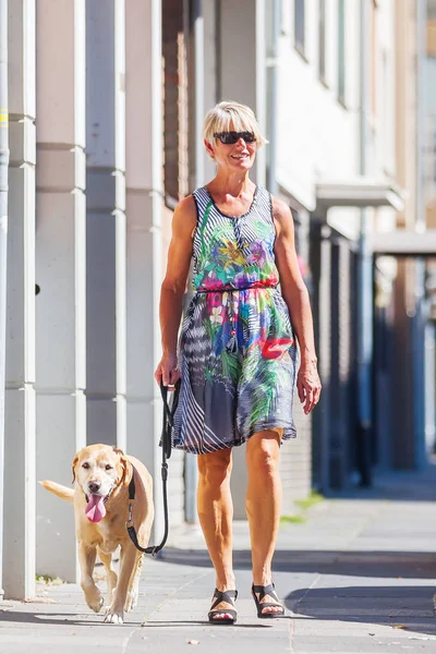 Женщина гуляет с собакой в городе — стоковое фото