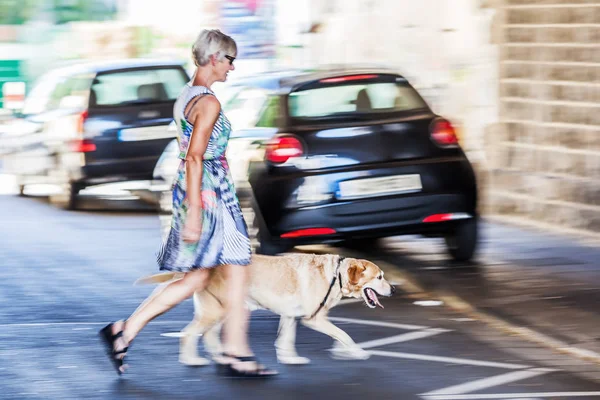 Mujer con perro cruzando una calle — Foto de Stock