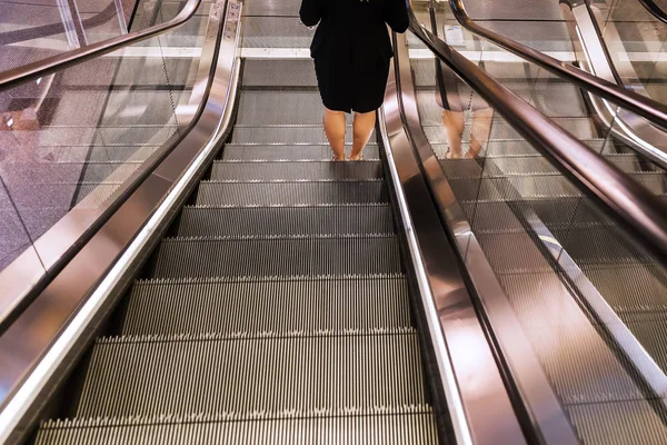 Escaleras mecánicas con las piernas de una mujer — Foto de Stock