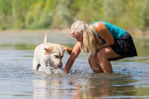 Woman plays with a dog in the lake — Stock Photo, Image