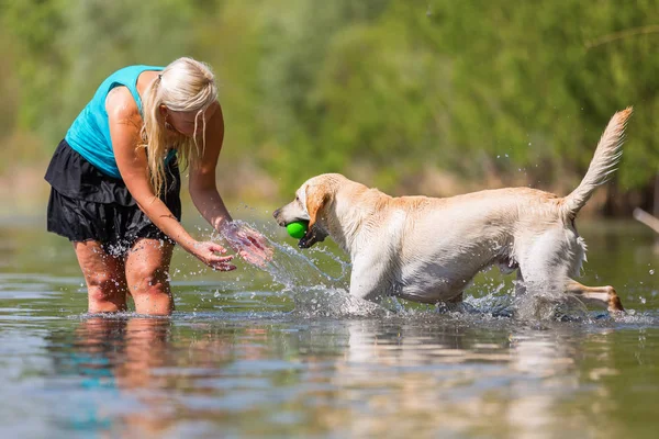 Wanita bermain dengan anjing di danau — Stok Foto