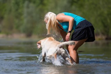 Olgun kadın gölde bir labrador çalış