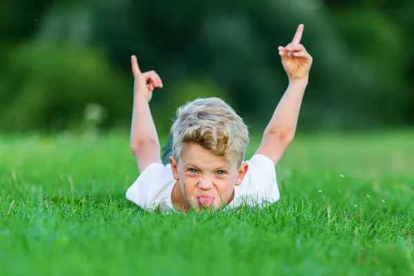 Ung pojke leker i gräset — Stockfoto