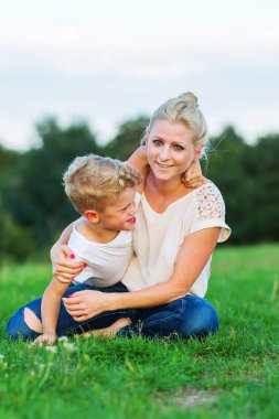 kadın oğluyla birlikte çimlere gebertiyor.