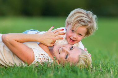 kadın oğluyla birlikte çimlere gebertiyor.