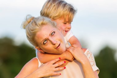 kadın oğluyla birlikte çimlere gebertiyor.