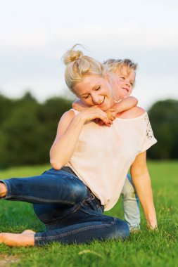 kadın oğluyla birlikte çimlere gebertiyor.