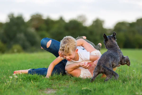 Mulher brinca com seu filho e um cão na grama — Fotografia de Stock