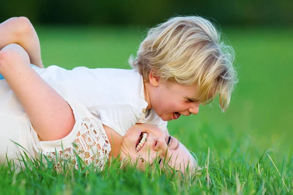 Mujer retoza con su hijo en la hierba — Foto de Stock