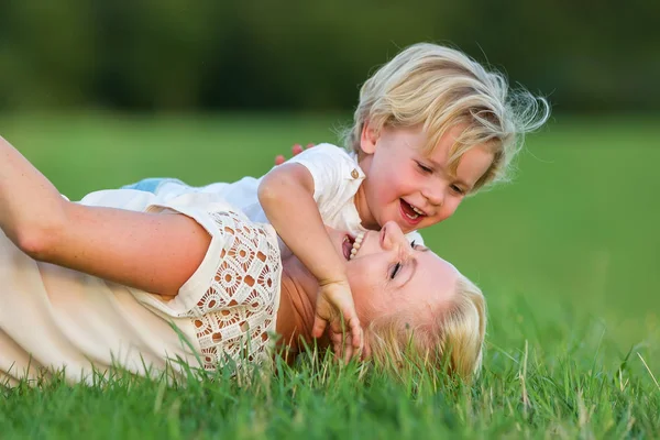 Mujer retoza con su hijo en la hierba — Foto de Stock