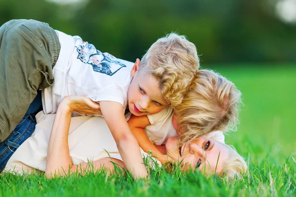 Mujer retoza con sus dos hijos en la hierba — Foto de Stock