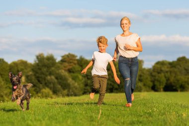 Anne oğlu ve bir köpek ile bir çayır üzerinde çalışır
