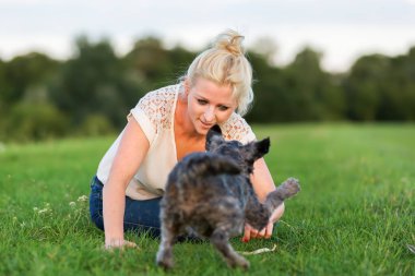 kadın bir çayır üzerinde korkunç melez köpeğiyle oynuyor
