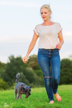 kadın bir çayır üzerinde korkunç melez köpeğiyle oynuyor
