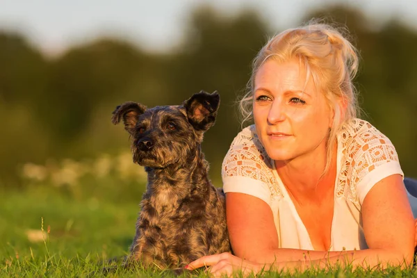 Mulher encontra-se com seu cão híbrido terrier na grama — Fotografia de Stock