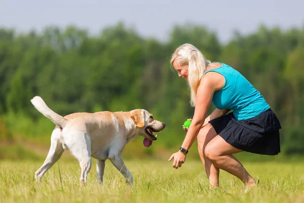 Bella donna gioca con il suo labrador retriever all'aperto — Foto Stock