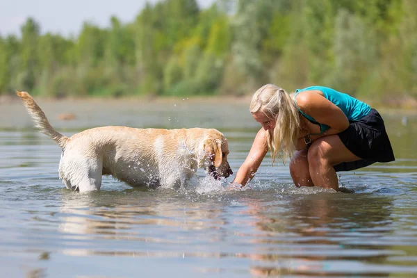 Wanita bermain dengan labrador retriever nya di danau — Stok Foto