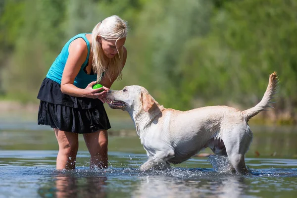 Woman plays with her labrador retriever in a lake — Stock Photo, Image