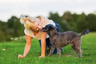 kadın bir çayır üzerinde korkunç melez köpeğiyle oynuyor