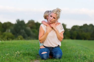 kadın oğluyla birlikte çimlere gebertiyor.