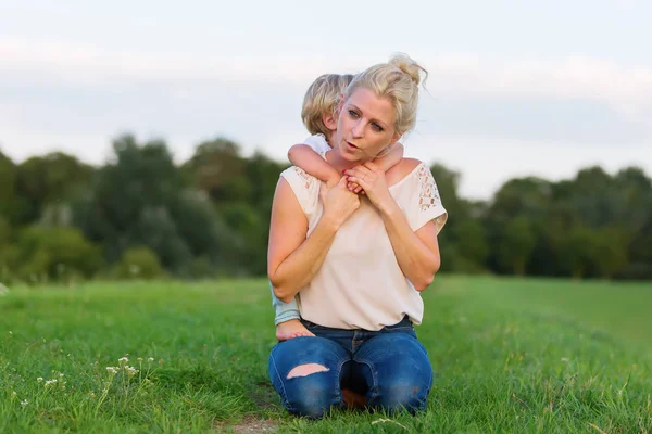 kadın oğluyla birlikte çimlere gebertiyor.