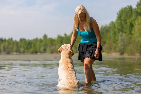 Woman plays with her labrador retriever in a lake — Stock Photo, Image