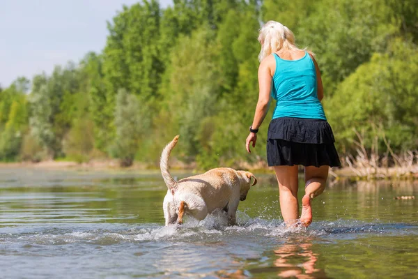 Woman plays with her labrador retriever in a lake — Stock Photo, Image