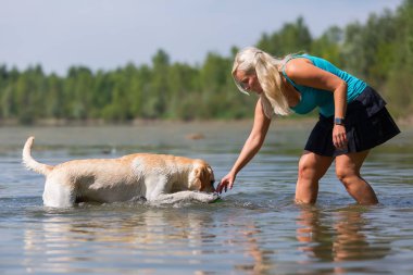 güzel bir kadın ile bir gölde bir labrador köpek çalış