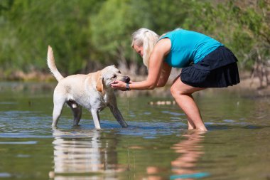 güzel bir kadın ile bir gölde bir labrador köpek çalış