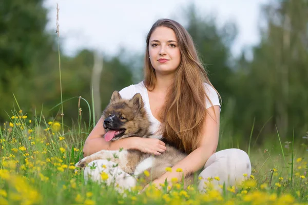 genç kadın bir Elo köpek çim ile oturur