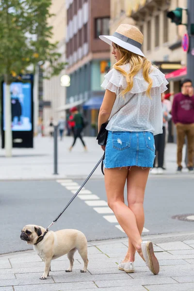 Mooie jonge vrouw met een mopshond wachten bij de voetgangersoversteekplaats — Stockfoto