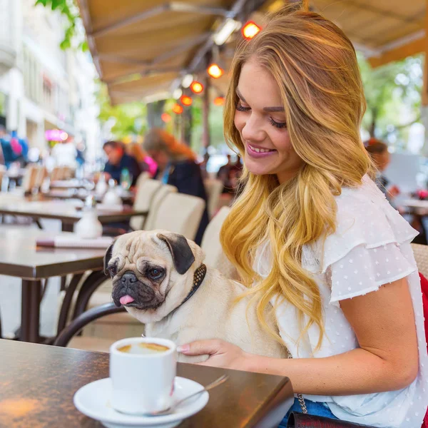 young woman with a pug in a street cafe