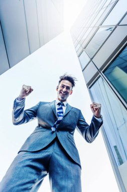 işadamı gökdelenler arasında duruyor ve bir kazanan yapar yumruk