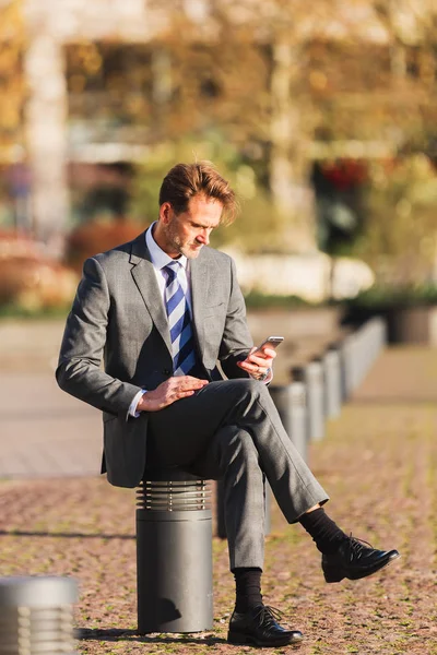 Hombre de negocios se sienta en un puesto con un teléfono celular — Foto de Stock