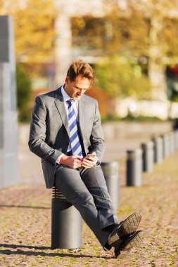 işadamı bir cep telefonu ile bir yazı üzerine oturur