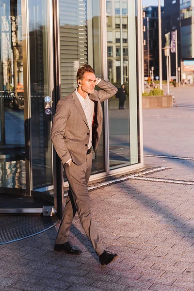 Businessman with earphones comes out of an office building — Stock Photo, Image