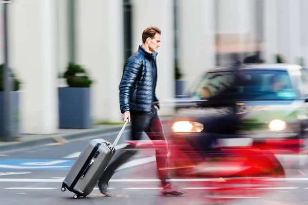 Businessman with trolley bag crosses the street — Stock Photo, Image