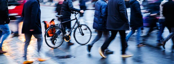Personnes et vélo traversant une rue de la ville au crépuscule — Photo