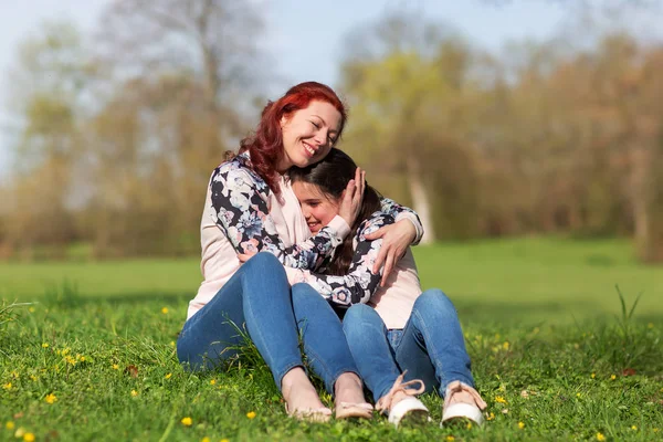 Madre e hija sentadas juntas en el césped — Foto de Stock