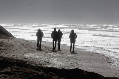 Fırtınalı denizde siluetli bir grup insanın fotoğrafı.