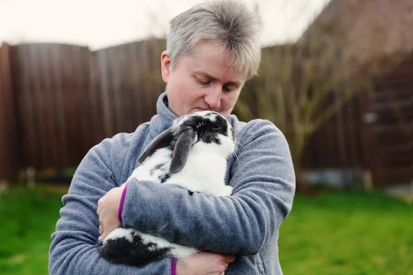 一个成熟的女人抱着一只宠物兔子 — 图库照片